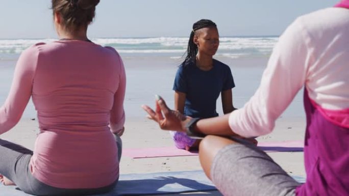 在沙滩和蓝天背景上做瑜伽的多民族妇女