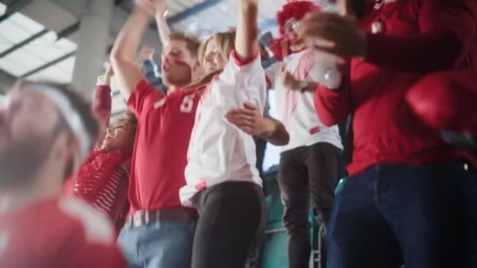 体育馆大事件: 一群球迷为红色足球队获胜而欢呼。人们庆祝进球，冠军胜利。可爱的白种人夫妇，脸上涂着脸