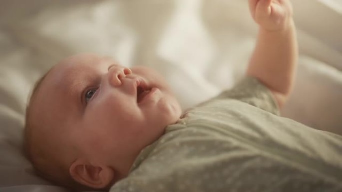 真实的特写镜头，一个可爱的新生婴儿躺在婴儿床的背上。一个高加索新生儿幼儿在舒适的家庭空间的俏皮肖像。