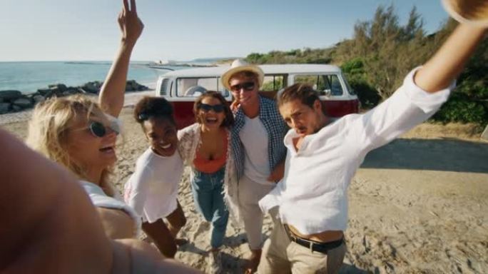 一群年轻的多种族朋友的慢动作很高兴用智能手机拍摄照片，而小型货车刚在海边的海滩上抵达。