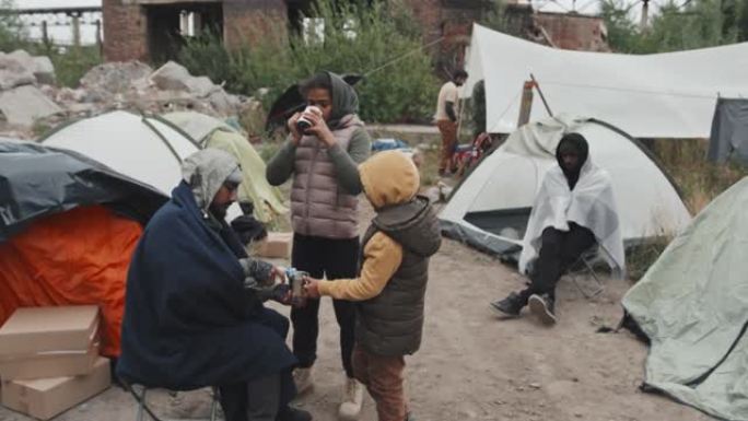 无家可归的儿童在难民营喝水
