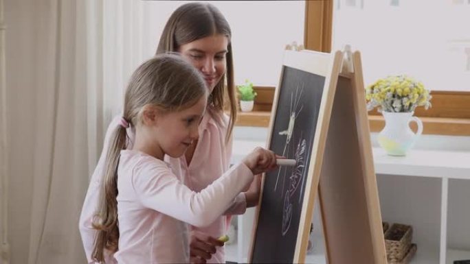 慈爱的母亲和小女儿用粉笔在船上画画