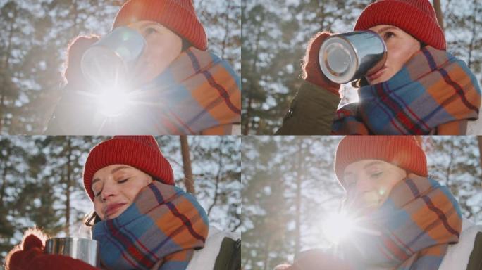 美丽的女人在冬天的徒步旅行中享受热茶