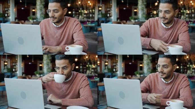 在尼斯咖啡馆用笔记本电脑喝咖啡的阿拉伯年轻人的慢动作肖像