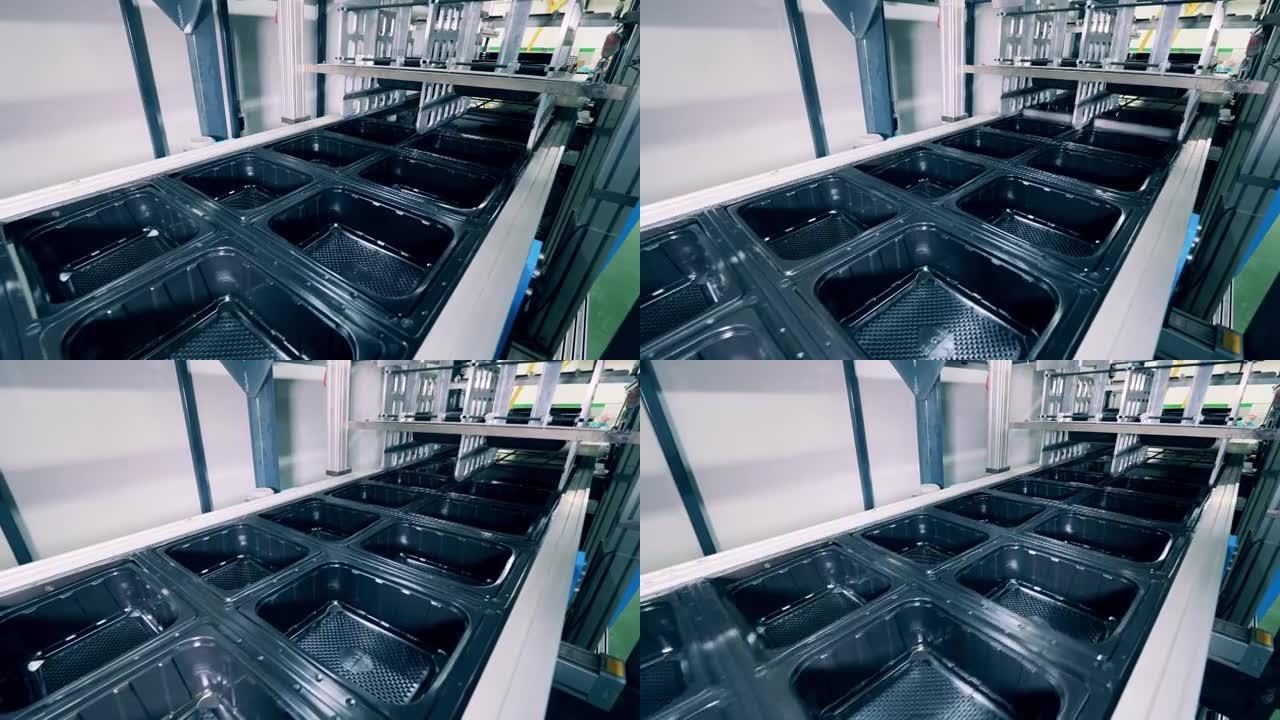 许多黑色塑料容器沿着输送机移动