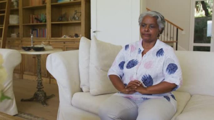 担心的非洲裔美国高级妇女坐在家里的沙发上
