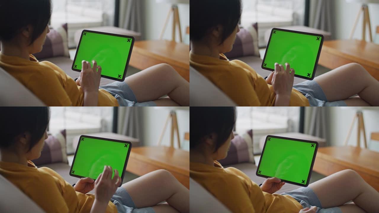 女人在家中使用带有绿屏的数字平板电脑