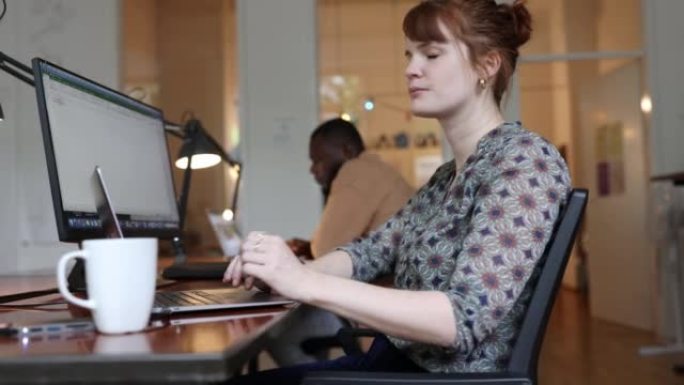 一个自信的女商人坐在创业办公室的办公桌前的肖像