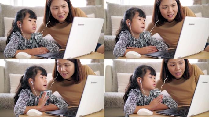 小女孩在家在妈妈的帮助下在客厅在线学习