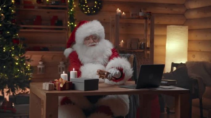 圣诞老人正坐在办公室的桌子上玩木制玩具飞机