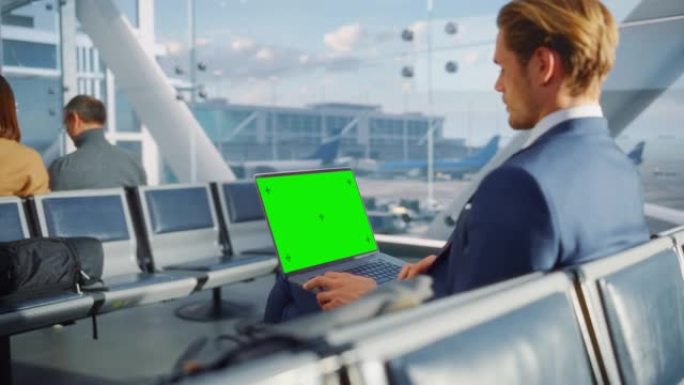 机场航站楼: 商人在等待飞机飞行时在绿色色度键屏幕笔记本电脑上工作。企业家在航空枢纽的登机休息室进行