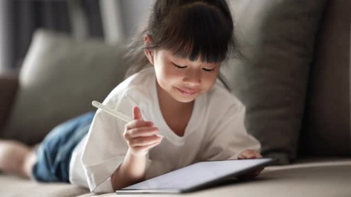小女孩在家中在数字平板电脑上写作以进行电子学习