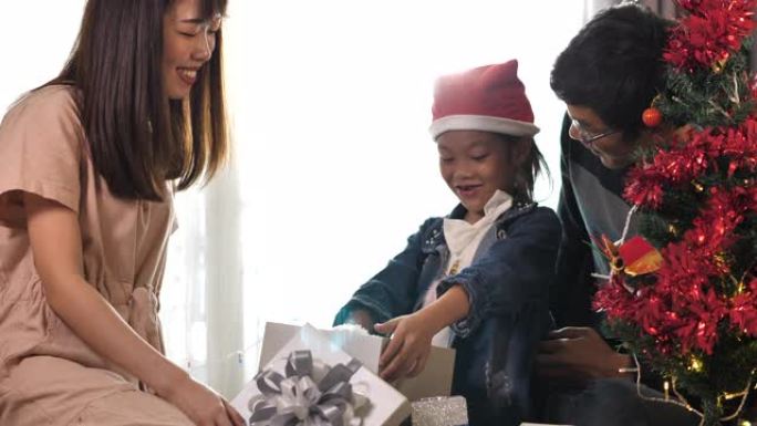 母亲和女儿在圣诞节那天在家与家人打开礼品盒