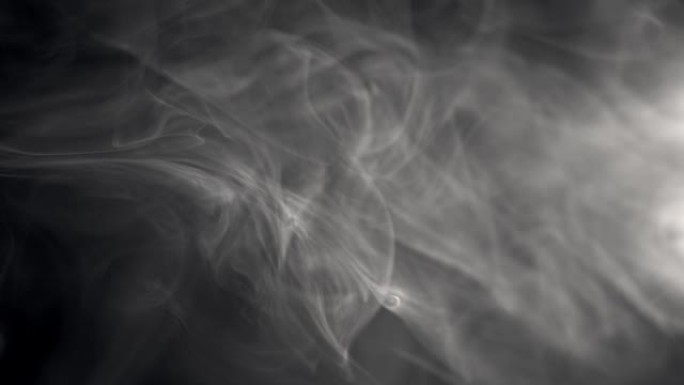 白烟的慢动作镜头漂浮在黑色背景上的空中。雾，火烟，蒸气在黑暗中缓慢移动