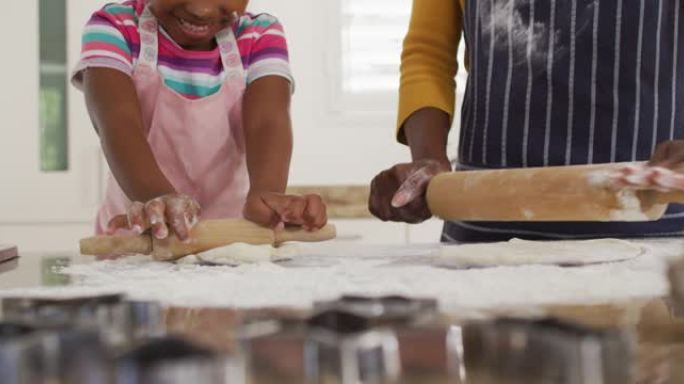 快乐的非洲裔美国母女在厨房里滚动面团