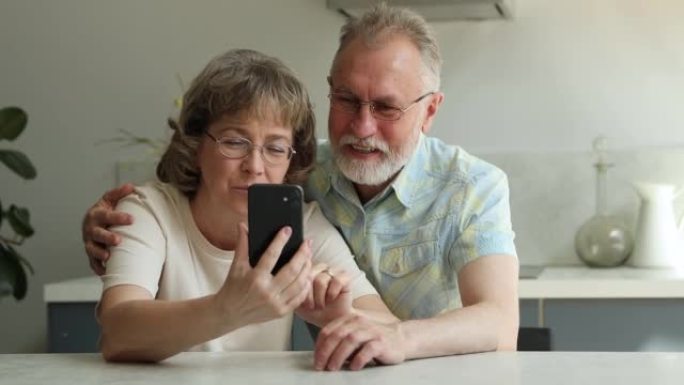 成熟的夫妇在家中使用新的移动应用程序拿着智能手机