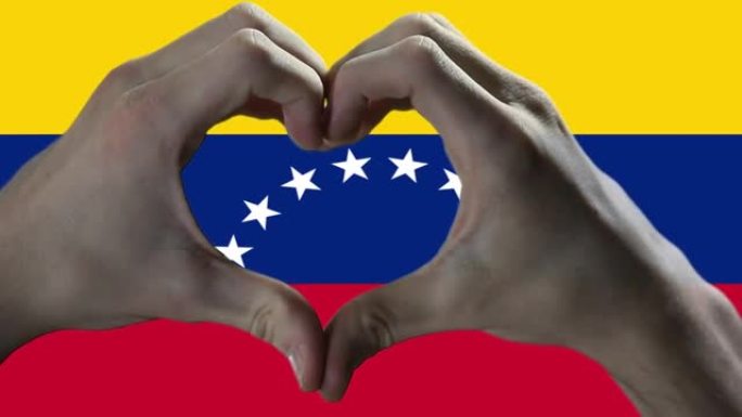 双手在委内瑞拉国旗上显示心脏标志。