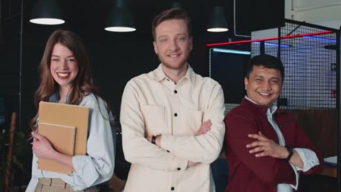 三位商业同事对着相机折叠手微笑的集体照。专业创意团队慢动作