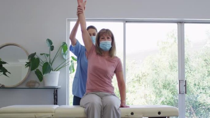 女卫生工作者在家中伸展高级妇女的手臂