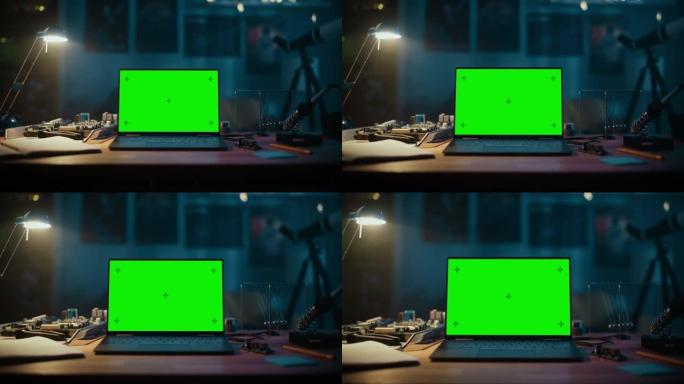 笔记本电脑站在一张绿屏Chromakey模拟显示器的桌子上。舒适的空房间，桌子上有灯，电路板，牛顿的