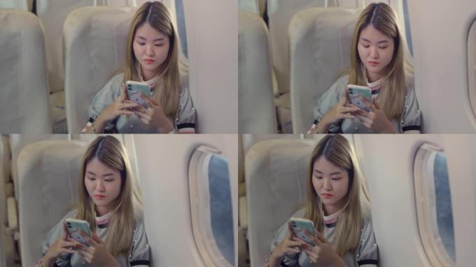 亚洲女性乘客晚上在飞机上使用智能手机