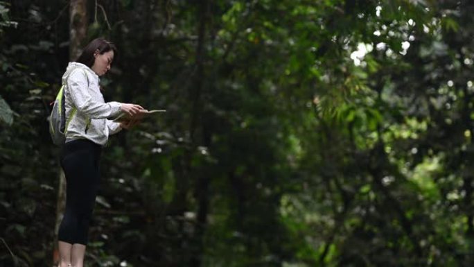 一位亚洲华裔美女在丛林雨林远足径中看着自己的地图
