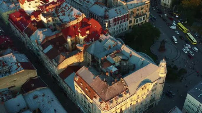 日出时，无人机在乌克兰利沃夫老城的真实生锈的历史住宅楼屋顶上低空飞行。
