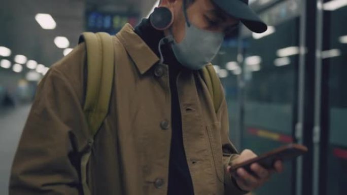 该男子的特写镜头正在等待地铁列车时站着并使用手机。
