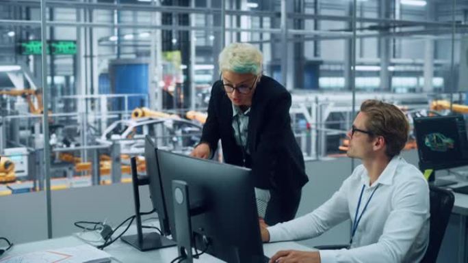两名汽车工程师在装配厂的现代办公室中讨论台式计算机上的概念车蓝图。女工业项目经理与车辆厂的男设计师交