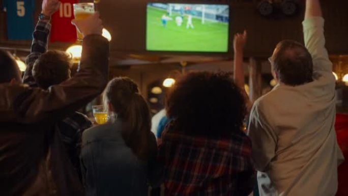一群多元文化的朋友在体育酒吧观看电视直播足球比赛。快乐的球迷欢呼雀跃。年轻人庆祝球队进球并赢得世界杯