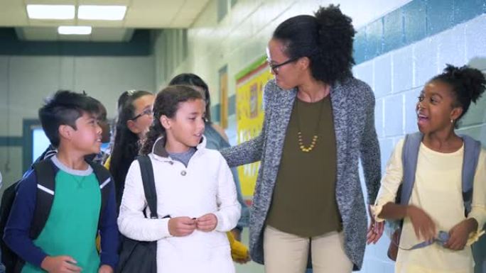 多种族教师和儿童在学校走廊上行走