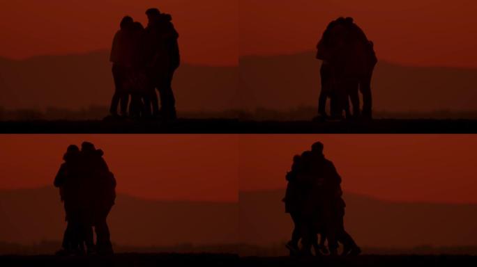 SLO MO在黄昏时拥抱在山上的剪影中充满爱心的家庭