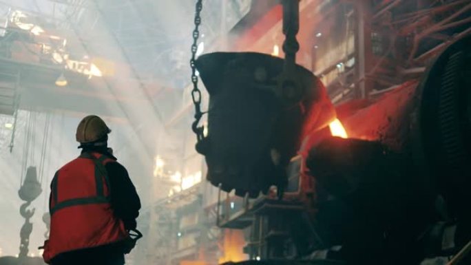 冶金工厂概念。钢铁工人正在观察熔化的金属从罐中倒出