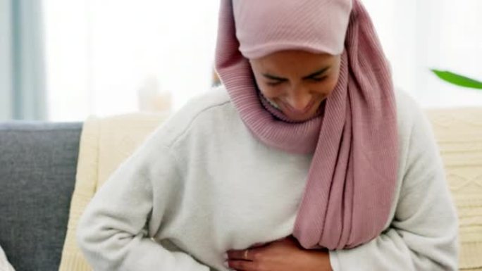 阿拉伯女人，月经和胃痛在家里客厅的沙发上独自痛苦。穆斯林女孩深呼吸，同时患有月经期间子宫疼痛。