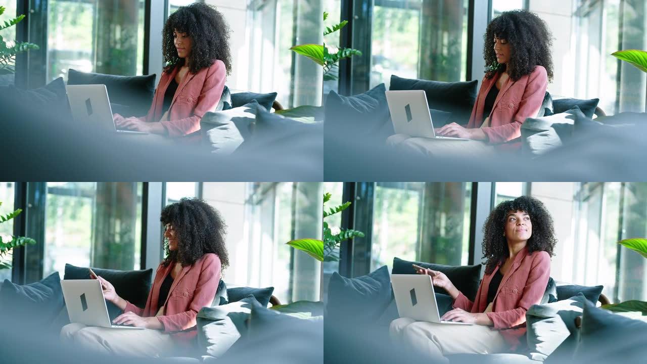 非洲女商人在办公室大厅的笔记本电脑上工作时检查手机