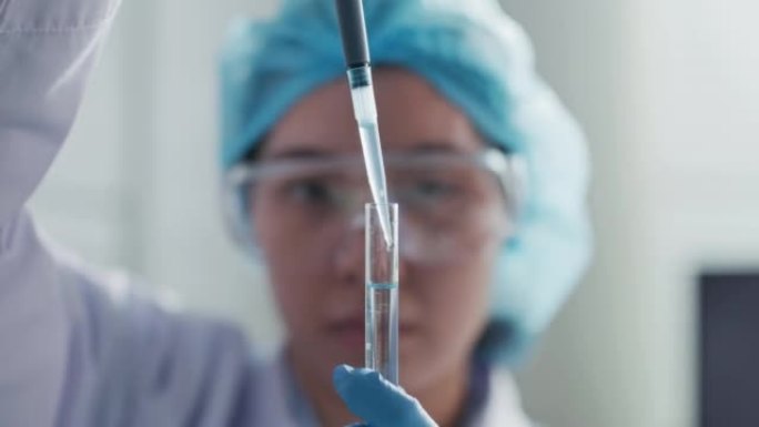 穿着白色防护服的女科学家使用移液器将化学物质填充到试管中