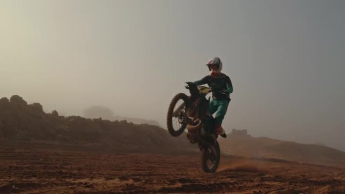 在沙漠土路比赛中的冒险路线上，男骑自行车的人在越野摩托车上做戏。摩托车骑手在大自然中练习耐力训练。积