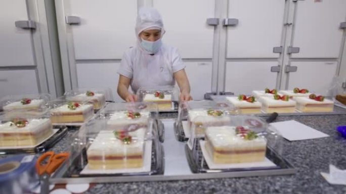 拉丁美洲妇女在食品加工厂用塑料容器包装甜点
