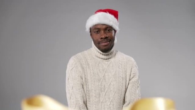 一个戴着圣诞帽和羊毛针织毛衣的黑皮肤男人微笑着