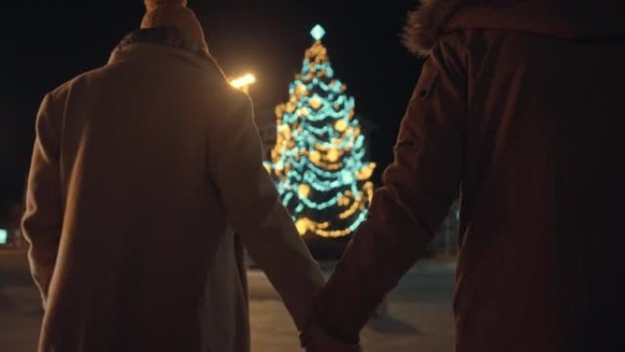 圣诞节期间，情侣手牵着手走在街上的后视图