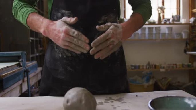 男性陶工在陶艺工作室的围裙上擦手的中段