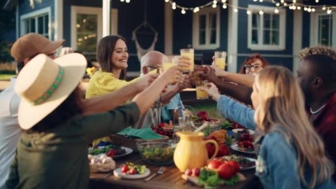 家庭和多民族的朋友聚集在花园餐桌上。老人和年轻人用新鲜的橙汁举起和碰杯，庆祝这一时刻。
