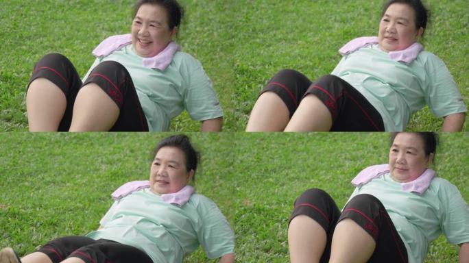 亚洲健康的高级女性在公园里做胃嘎吱嘎吱。老年女性在绿色玻璃上锻炼。早上做腹部核心运动，让老祖母在户外