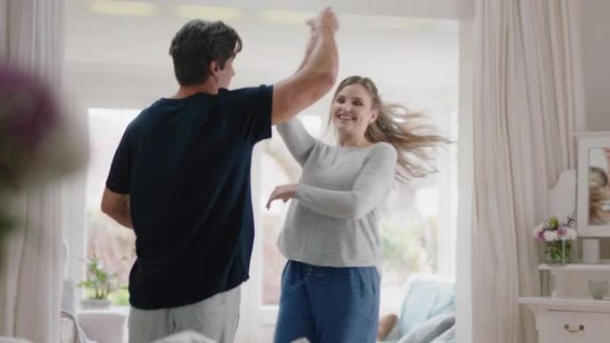 快乐的年轻夫妇在家跳舞庆祝周末早上一起享受有趣的舞蹈在卧室成功的关系庆祝4k镜头