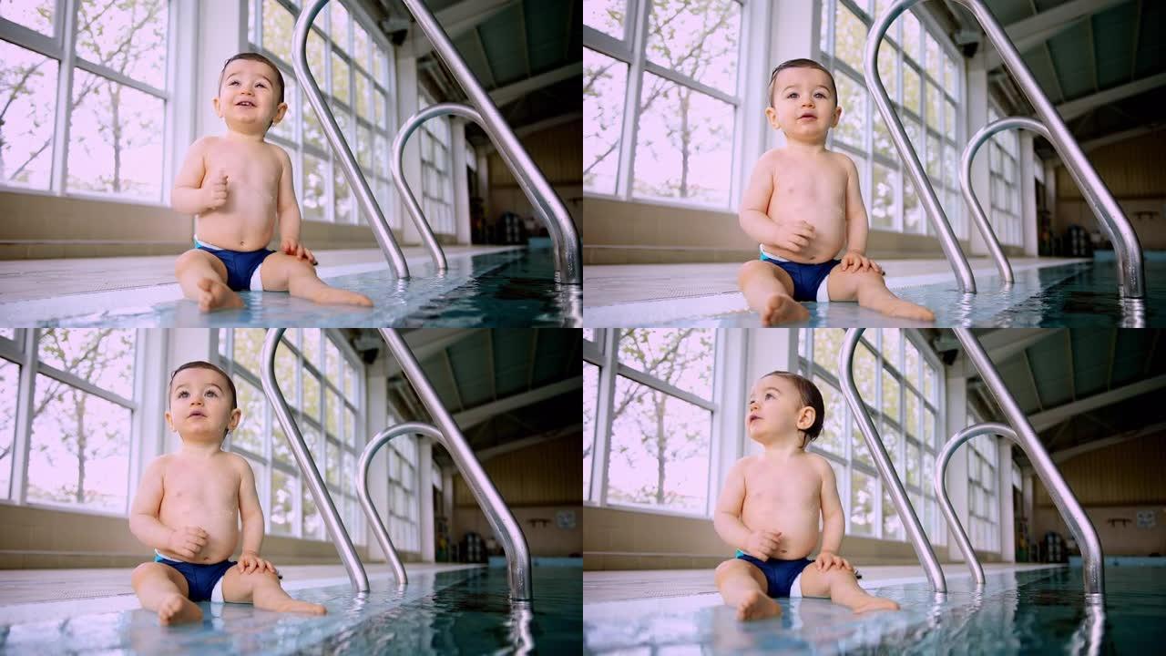 可爱的婴儿坐在室内游泳池的侧边