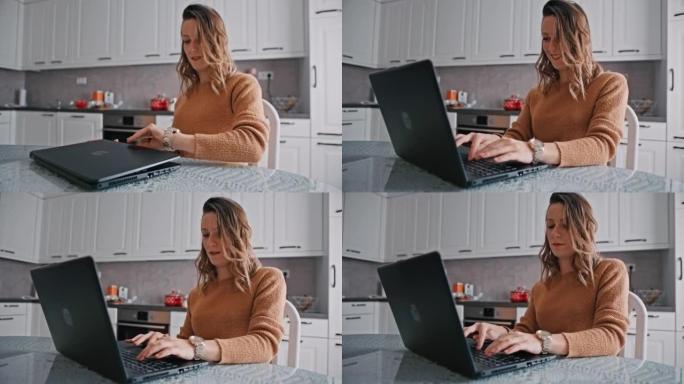 坐在厨房餐桌上的女人在笔记本电脑上工作