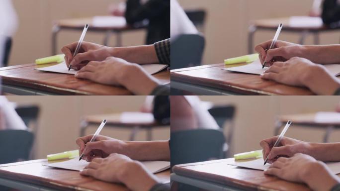 4k录像片段，一个十几岁的男孩在高中教室里的桌子上写字