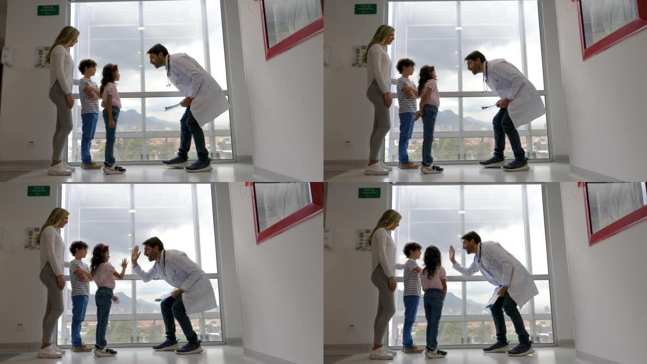 快乐的拉丁美洲家庭医生和他们的妈妈在医院给可爱的男孩和女孩击掌
