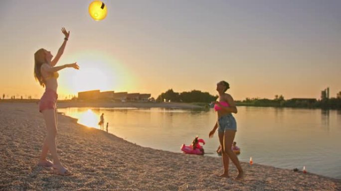 SLO MO两名年轻女子在海滩上传递沙滩球