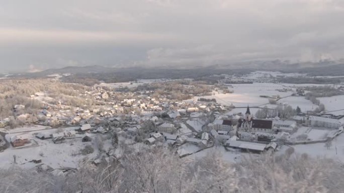 空中: 冬季早晨的阳光照亮了雪谷和郊区村庄。